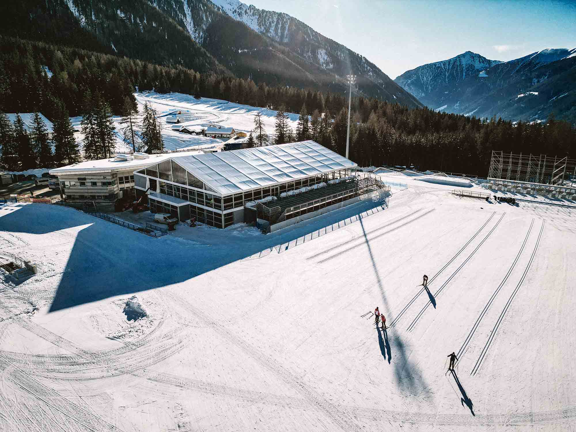 A snow-covered building and some people skiing in the Anterselva valley
