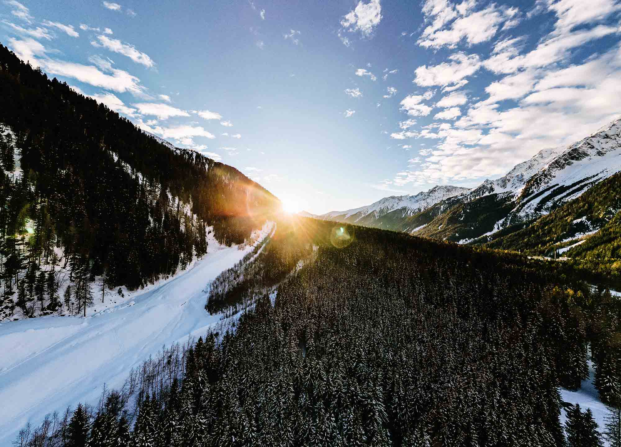 The sun shines through the snow-capped mountains of Anterselva