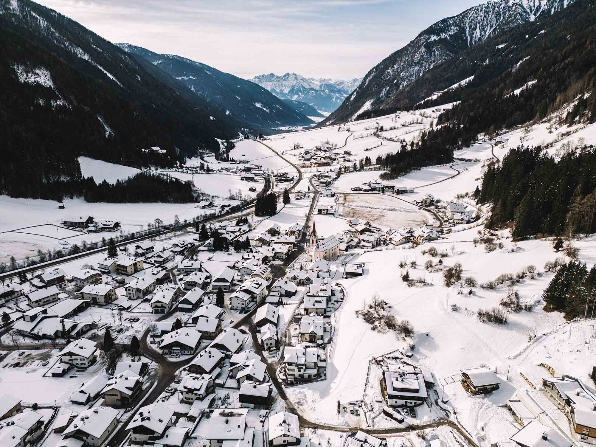 Aerial image of a small inhabited center amidst the snowy mountains in Anterselva