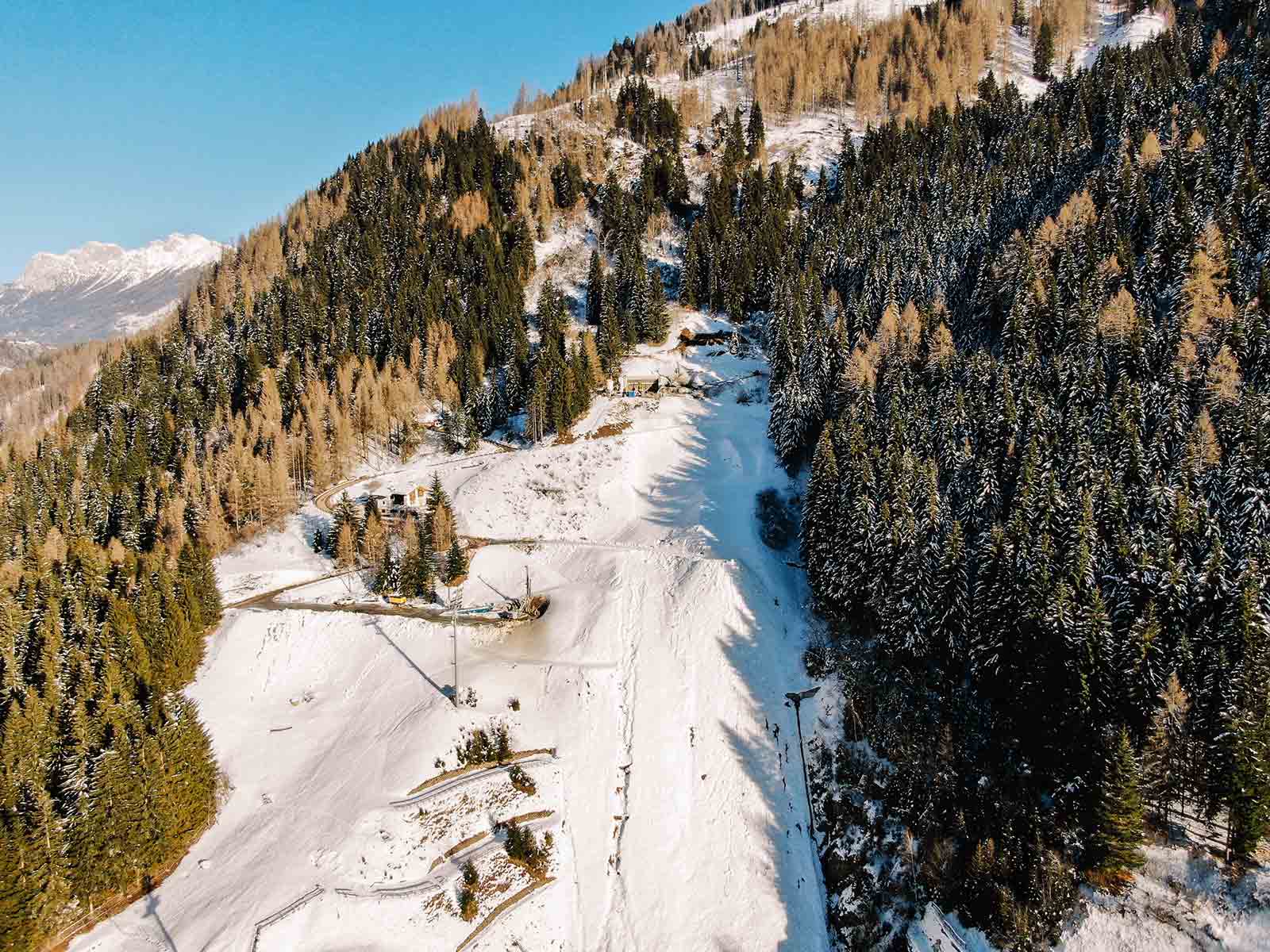 A ski slope surrounded by trees and snow on the mountains of Predazzo.