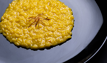 un piatto nero con un risotto giallo e zafferano