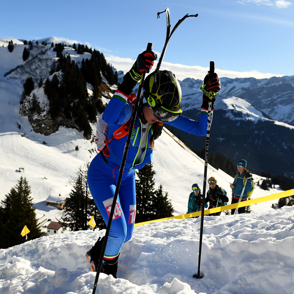 uno sciatore che indossa un abito blu e verde è in cima a una montagna innevata 