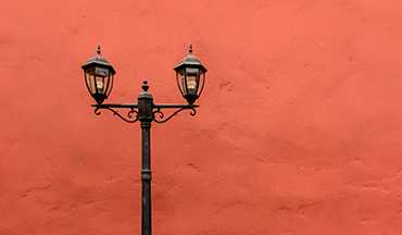 un lampione con due luci davanti a un muro rosso