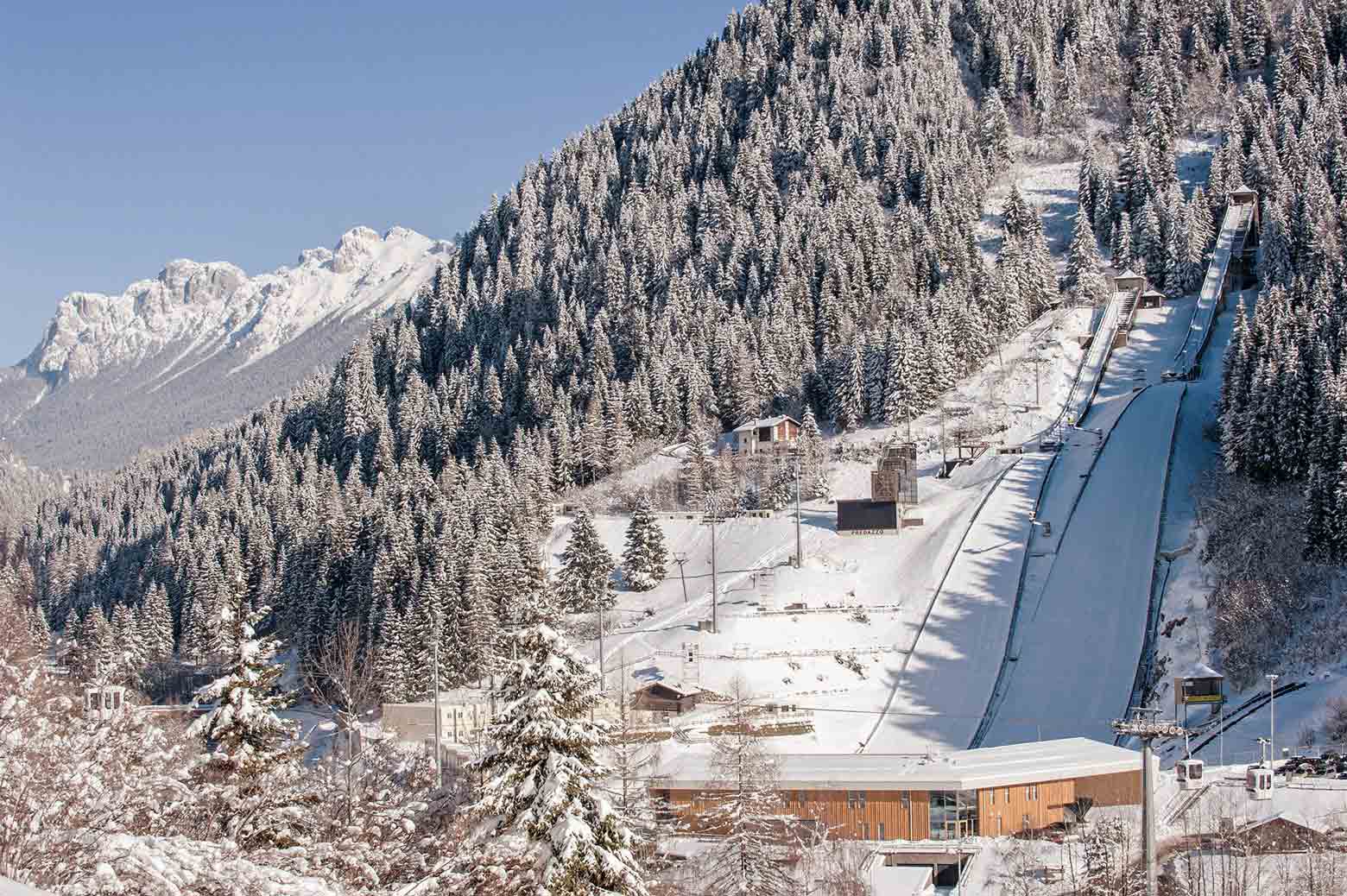 Paesaggio invernale con pista da sci e alberi innevati a Predazzo.