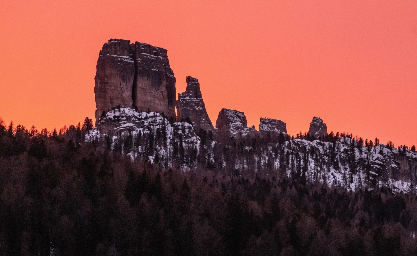 A red sunset over the mountains and snow-covered trees in Cortina d'Ampezzo.