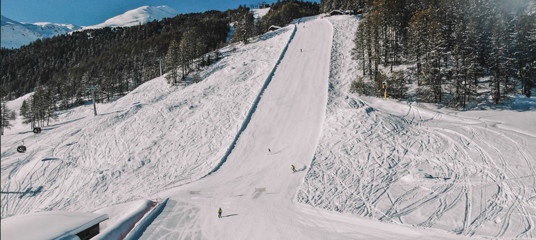 un gruppo di sciatori scende lungo la pista innevata del Parco Arials & Moguls​ di Livigno