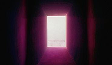 una porta rosa è aperta in un corridoio buio