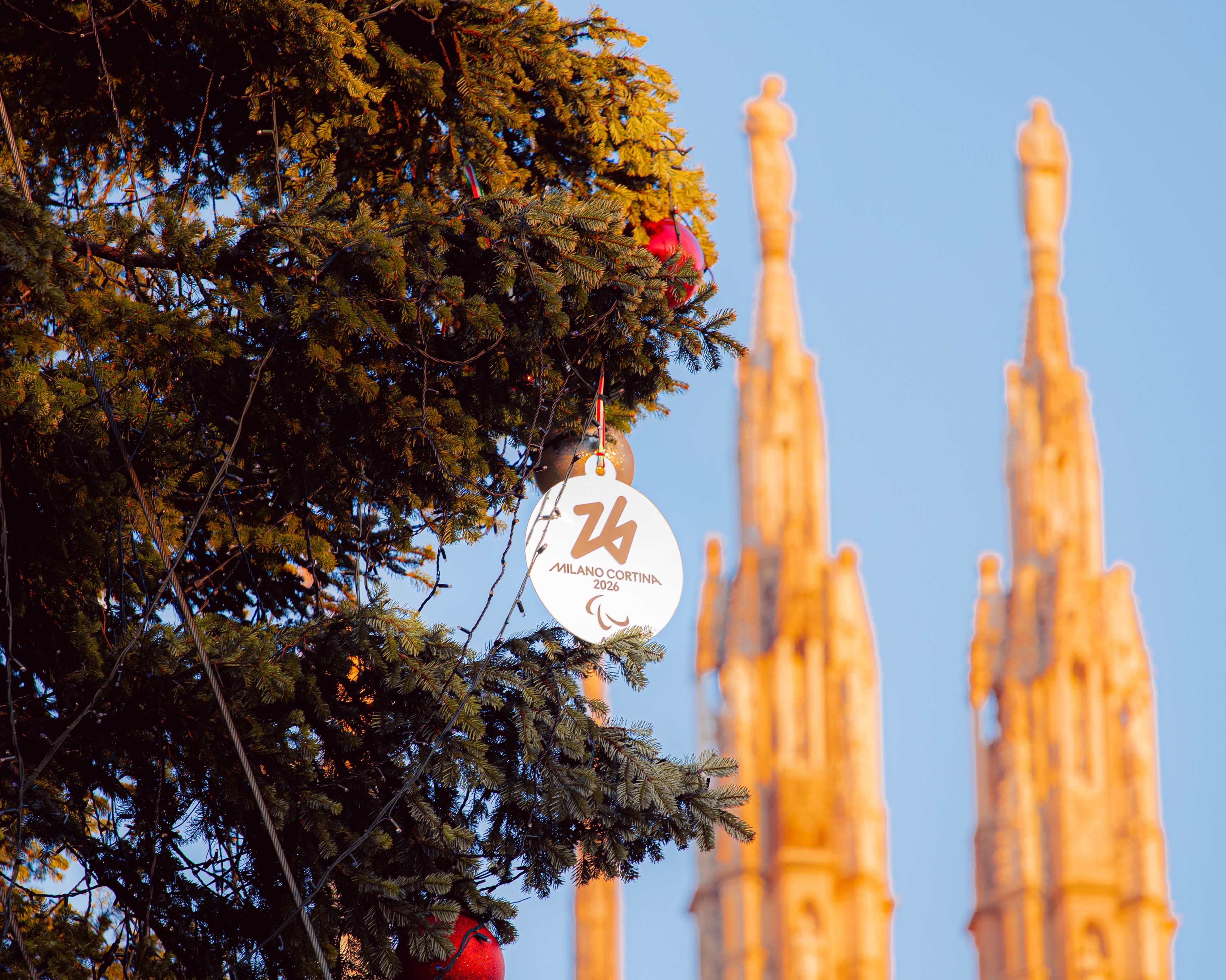 Photo de détail de la médaille de Milan Cortina 2026 suspendue à une branche de l'arbre de Noël placé sur la Piazza Duomo