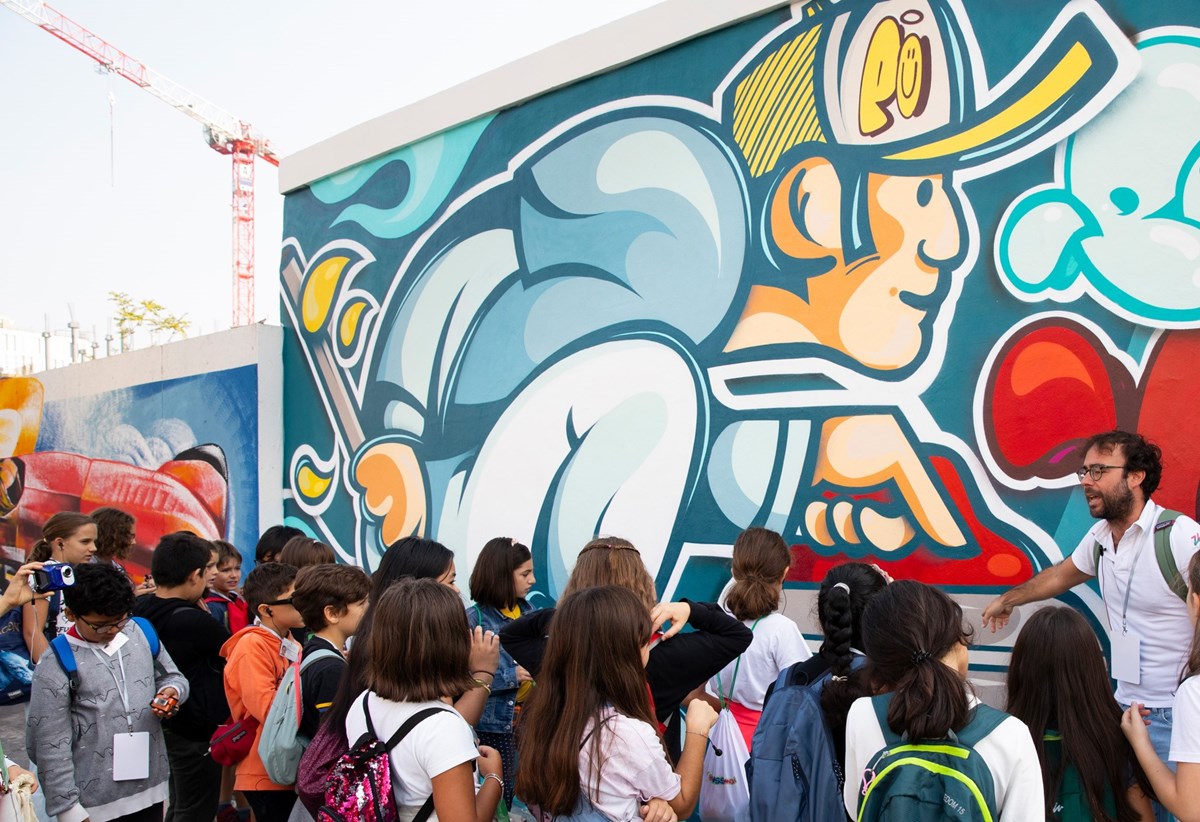 Foto di un gruppo di bambini mentre guardano il murales