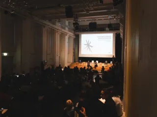 Foto della sala del BASE piena di persone mentre ascoltano il talk