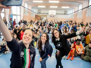 Three women take a selfie with a group of kids