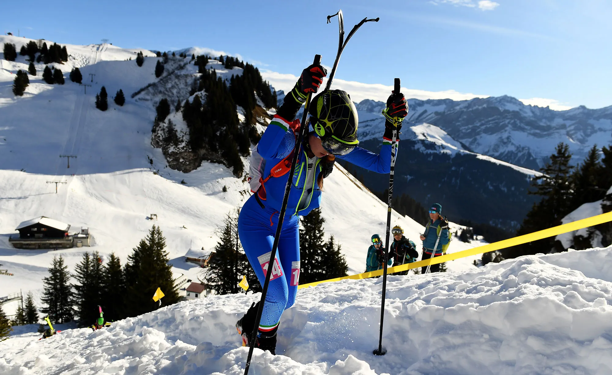 eine stehende Frau, die auf dem Gipfel eines verschneiten Berges Skitouren geht